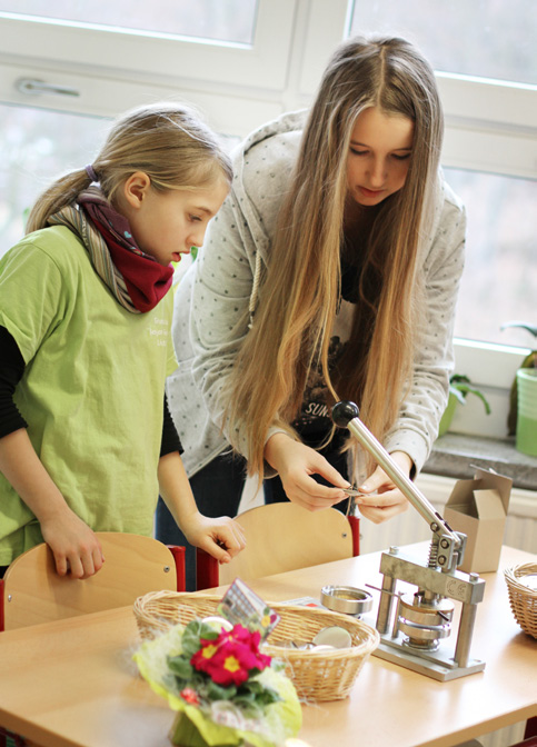 Anna Karina Kemper hilft den Kindern beim Pressen der Buttons